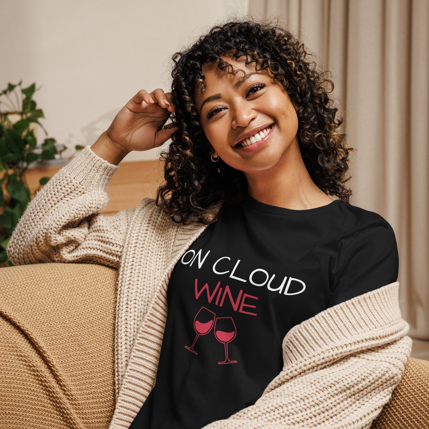 Smiling woman in black "On Cloud Wine" relaxed t-shirt, cozy cardigan, enjoying a casual moment at home.